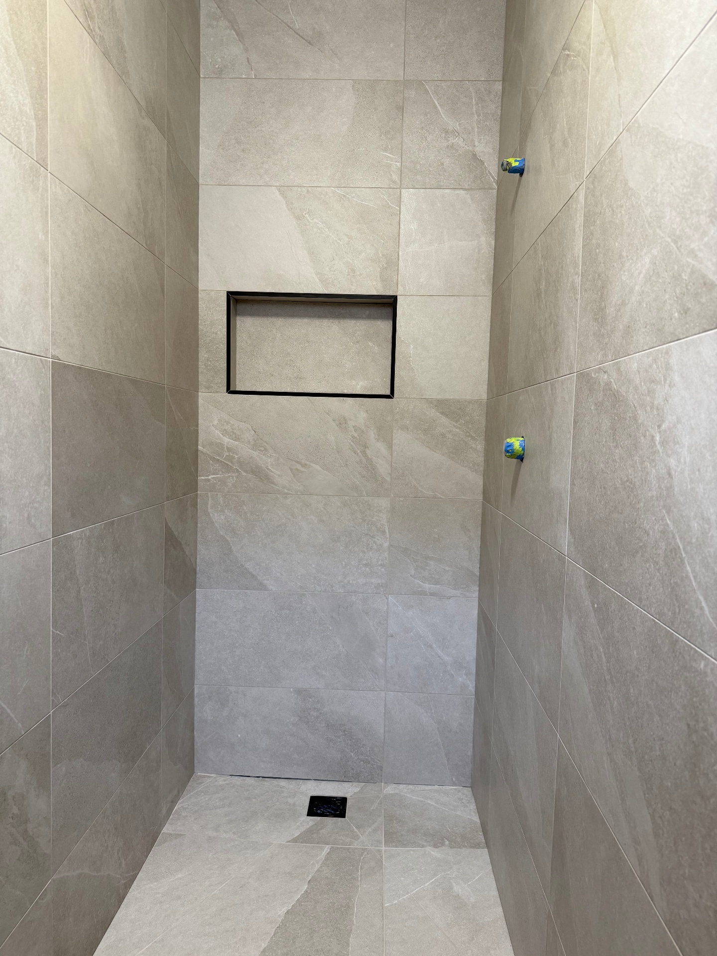 Tiled shower recess with framed matte black feature niche mid-build