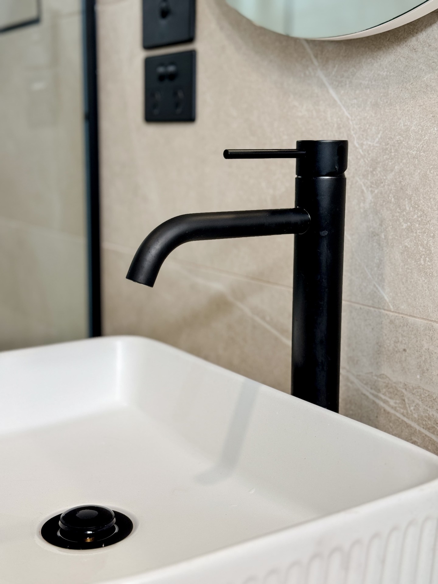 Matte black basin mixer over fluted vessel basin