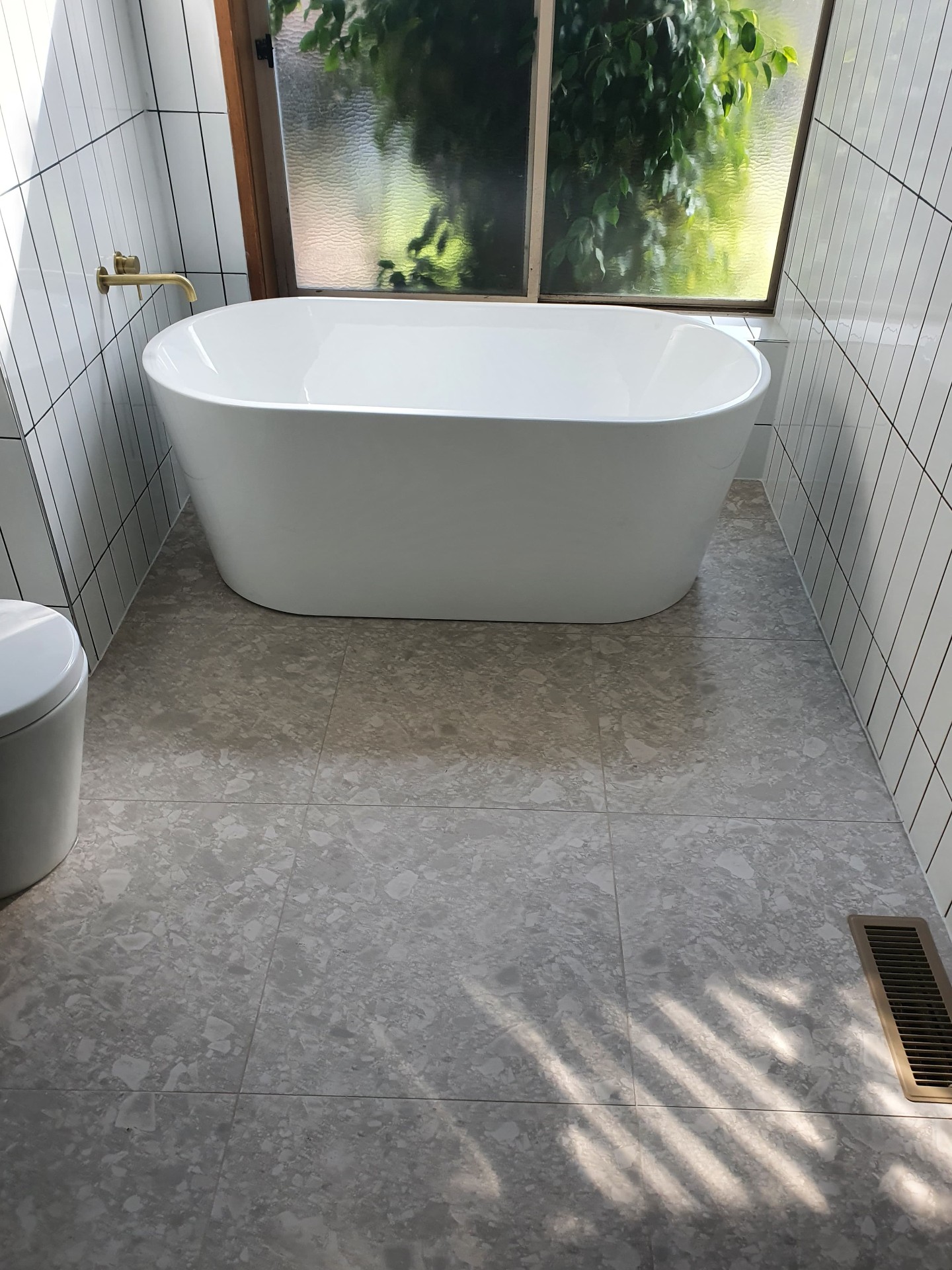 Freestanding white bath with terrazzo-look floor tiles