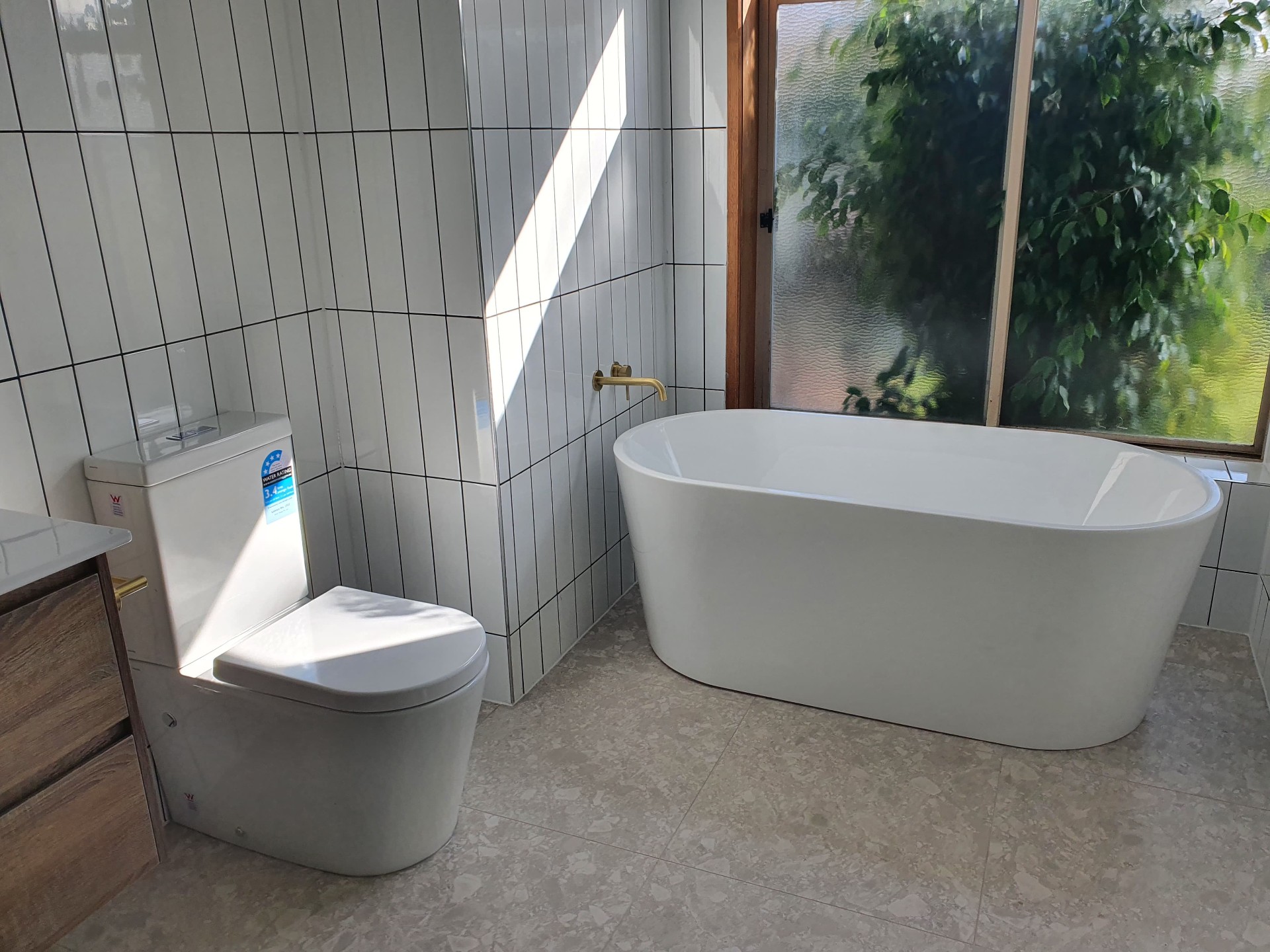 Wide view of toilet and freestanding bath with garden outlook