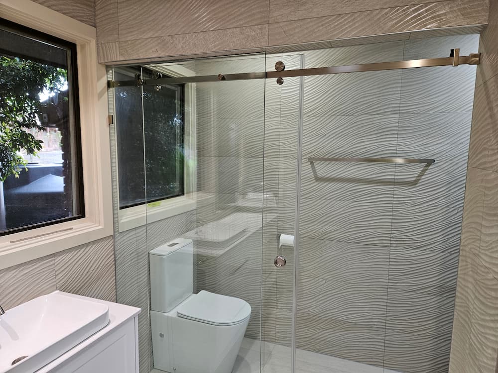 Frameless sliding glass shower with brushed brass hardware