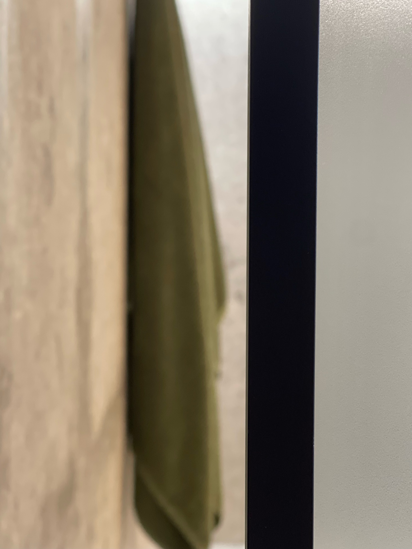 Detail of timber-look tiles, sage towel and matte black shower frame