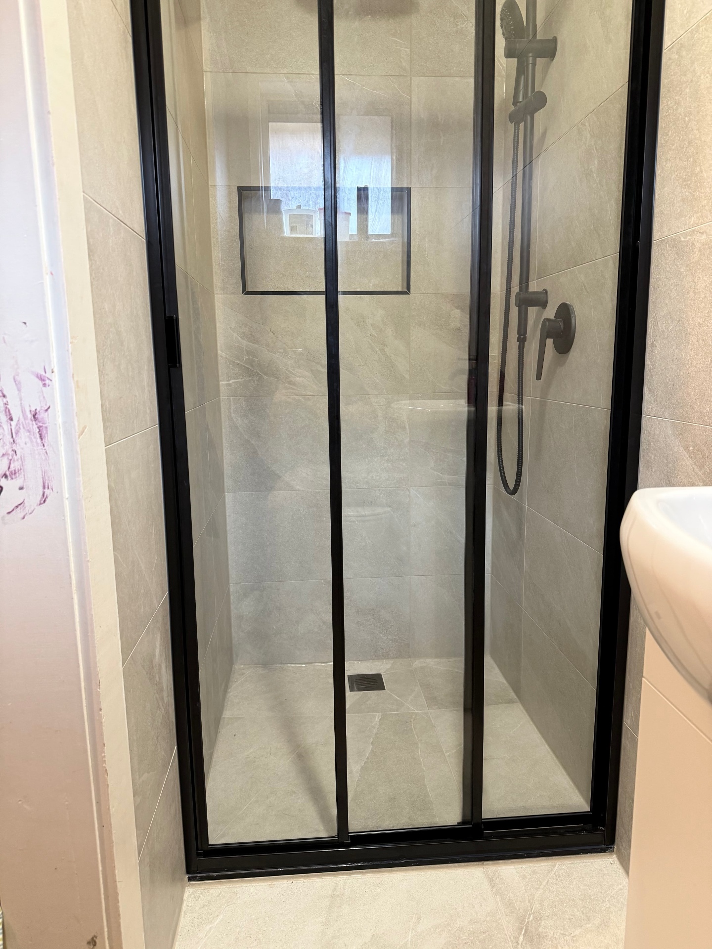 Newly tiled shower with large-format stone-look porcelain & matte black framed niche